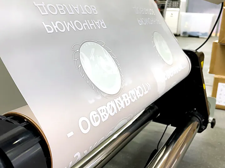 Плёнка с напечатанными принтами выходит из DTF-принтера в цехе Печатыча