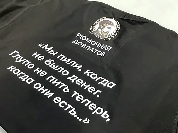 Крупный план готового белого принта с логотипом на чёрной футболке